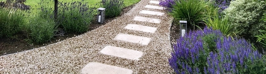 Acél járdaszegély egy kerti ösvény mentén, ültetéssel